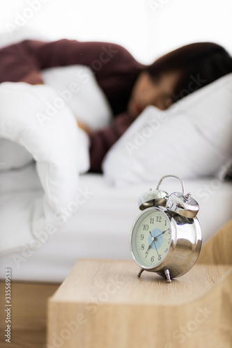 alarm clock on table with sleepy woman in the morning with late wake up. stay at home, work from home and working woman concept.