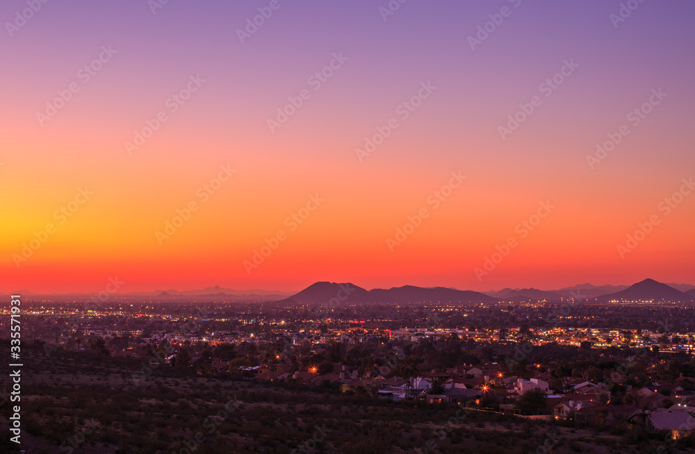 Sweeping views of desert mountains and small neighborhoods under skies that rapidly change vibrant colors as the sun sets in the southwest USA