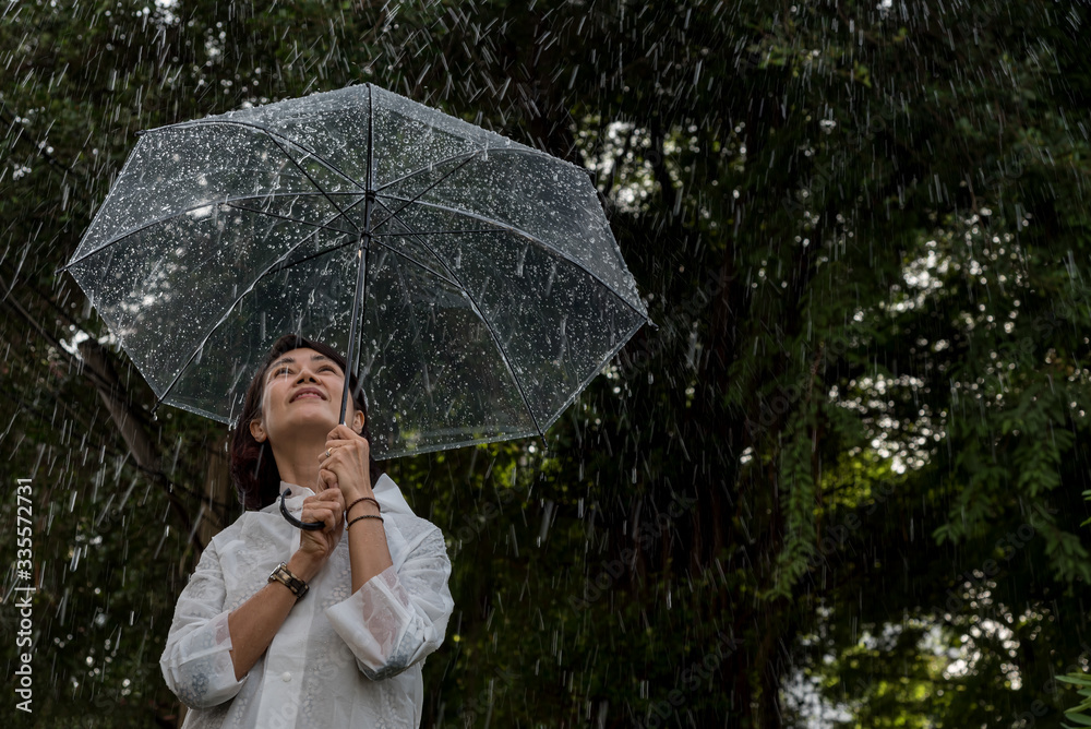 In raining day woman open umbrella stand in garden feel happyand have warmth,romantic feeling.