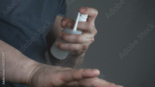 A man sprays an antiseptic on his hands. photo