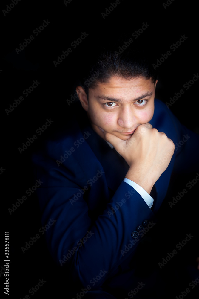 Portrait shot of businessman posing with classic look. Businessman with a classic thoughtful look over black background in the dark blue colored suit. Vertical shot.
