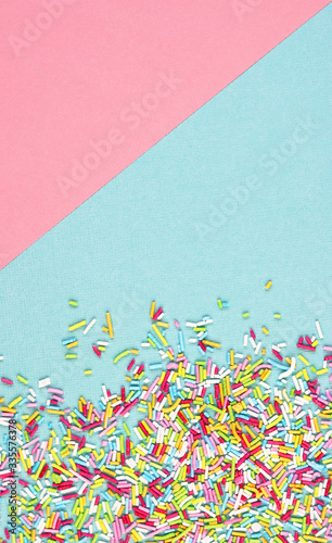 culinary pastry rainbow sprinkles are scattered on a pink and blue background