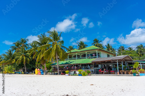 Gorgeous tropical sandy beach with palm trees  blue sky and clear water.