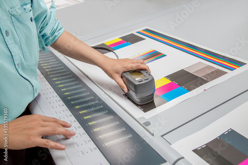 オフセット印刷において印刷物の濃度を測定する手元のアップ。カラーマネージメント、品質管理イメージ