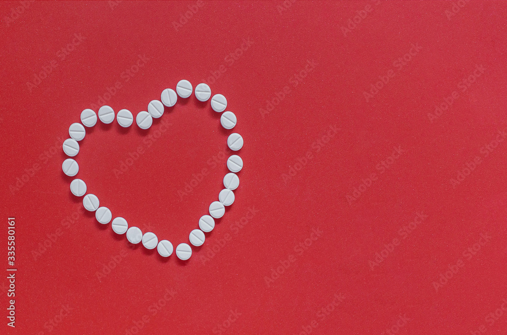 
heart made of white pills on a red background