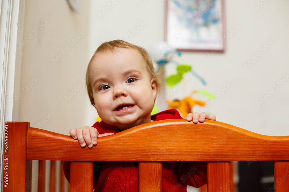 little child girl in a red sweater, smiles beautifully, in a crib, plays and has fun, emotional photo little child girl in a red sweater, smiles beautifully, in a crib, plays and has fun, emotional photo