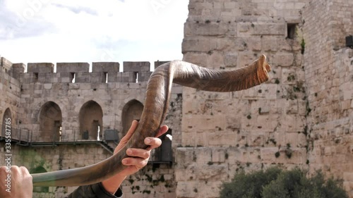 Jewish men blowing shofar in Jerusalem. Israel. The ancient walls of the old town, the City of David is on the background.