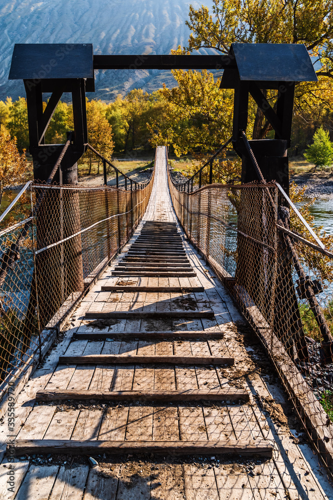 Suspension bridge over a mountain river in a gorge. Russia, Altai Republic, Ulagansky District, Chulyshman River Suspension bridge over a mountain river in a gorge. Russia, Altai Republic, Ulagansky District, Chulyshman River