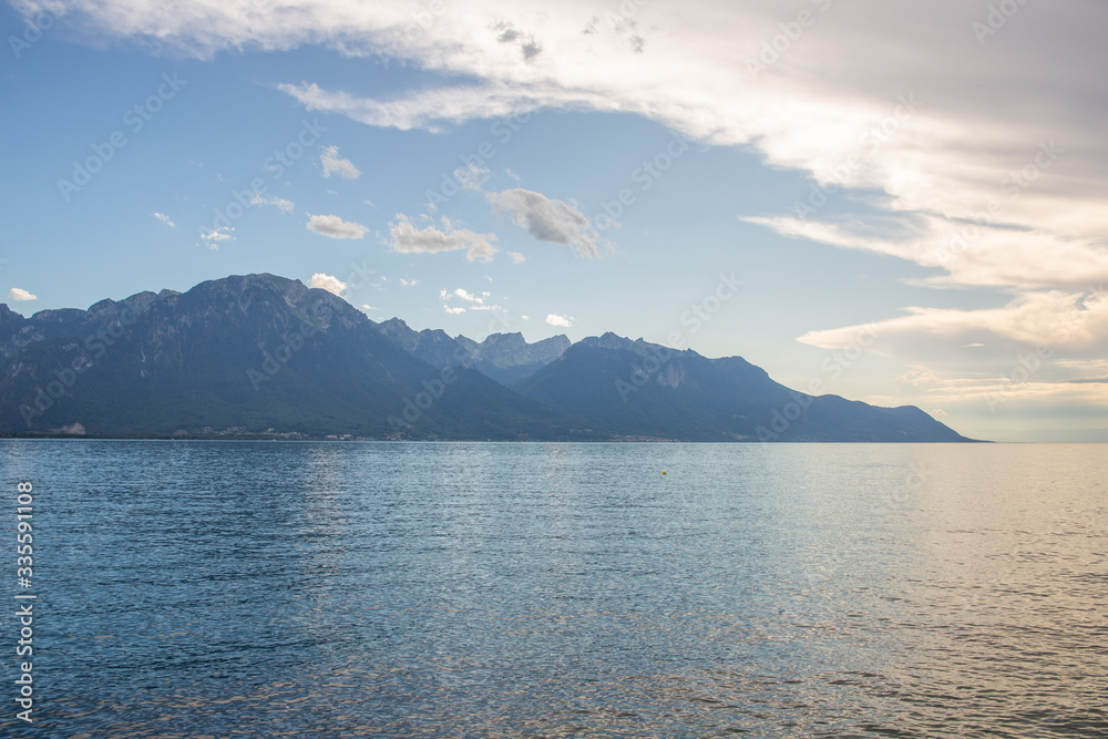 Smooth, radiant water surface and distant mountains at sunset, lake panorama