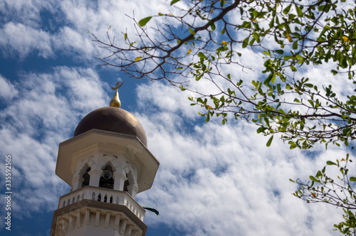 Minaret with green plant at Masjid Kapitan Keling under blue cloudy day, photo