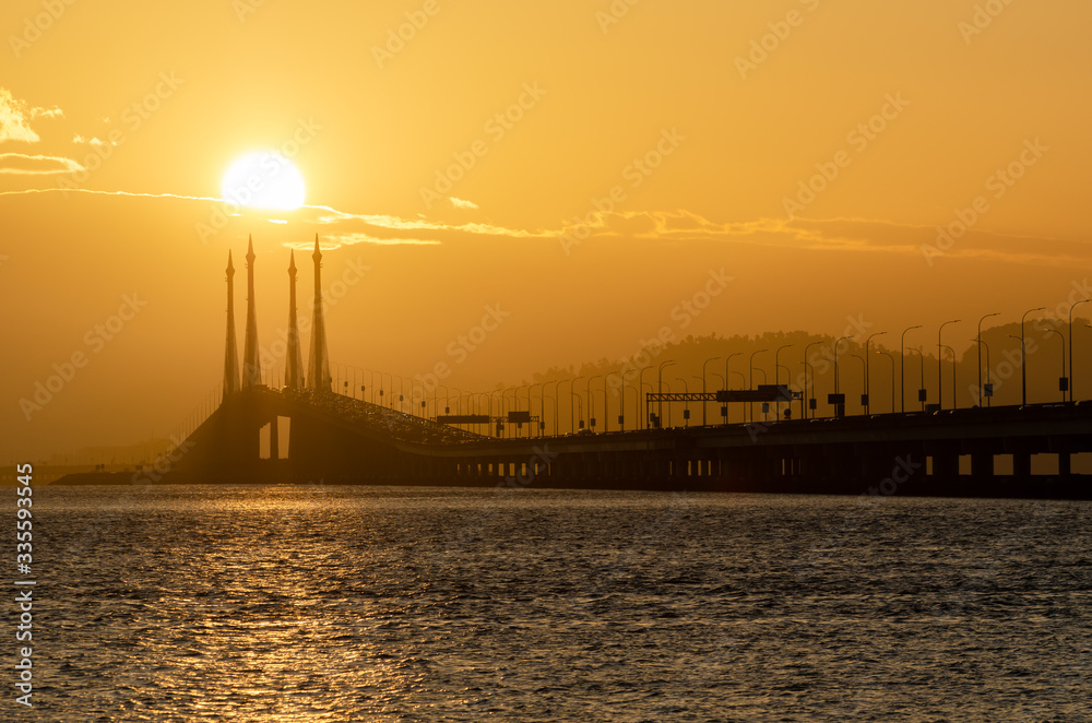 Egg yolk sunrise over central span of Penang Bridge.