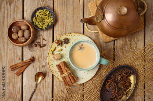 Masala chai tea traditional indian drink  with milk and spices on wooden background. Top view from above