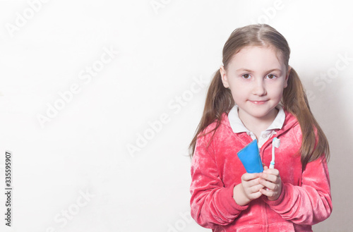 a girl holds a toothpaste and brush on a white background with a copy space