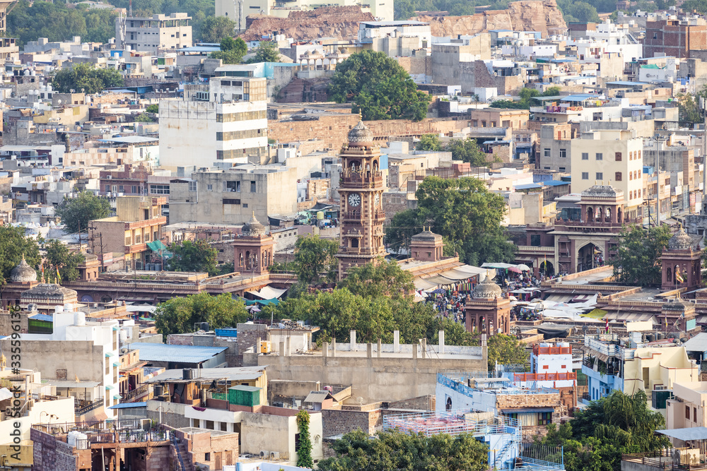Stunning aerial view of the Jodhpur Blue City with the Clock Tower (Ghanta Ghar) and people walking in the Sardar Market. Jodhpur is a city in the Thar Desert of the northwest India.
