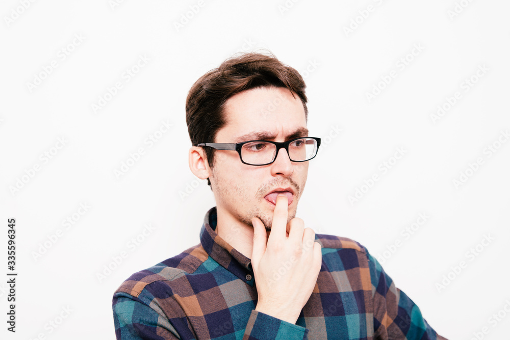male of European appearance causes vomiting putting his fingers in his mouth on a gray background, nausea