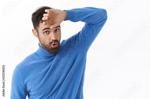 Phew that was close. Portrait of relieved handsome bearded man wiping sweat from forehead and exhale as got rid of problem, finished task, feeling exhausted, standing white background