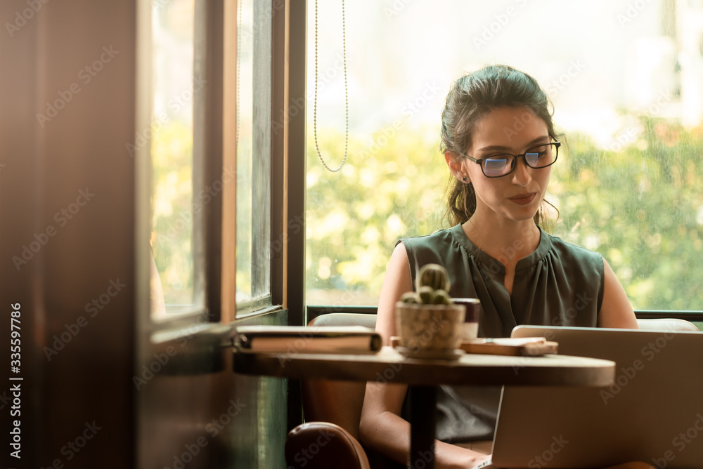 Beautiful caucacsian woman wear glasses use internet via laptop in cafe during morning Beautiful caucacsian woman wear glasses use internet via laptop in cafe during morning