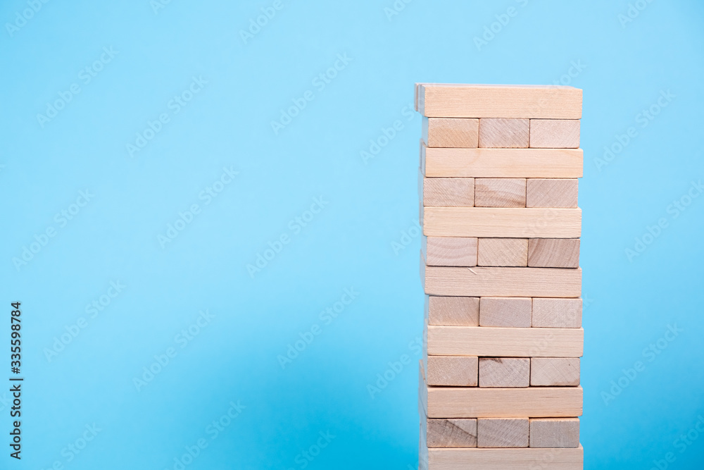 The tower is made of wooden blocks. Jenga close-up. On a blue background