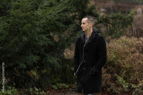 Profile of Young Man with Earphones in Autumnal Park Background