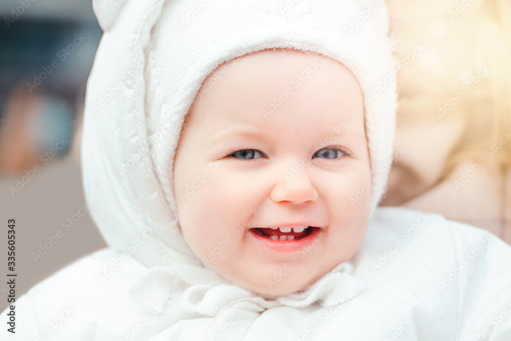 Portrait of a cute smiling Caucasian baby girl outside. Child toddler in white warm clothes walking outdoor. Laughing funny lovely young kid with blue eyes. Happy childhood lifestyle. Portrait of a cute smiling Caucasian baby girl outside. Child toddler in white warm clothes walking outdoor. Laughing funny lovely young kid with blue eyes. Happy childhood lifestyle.