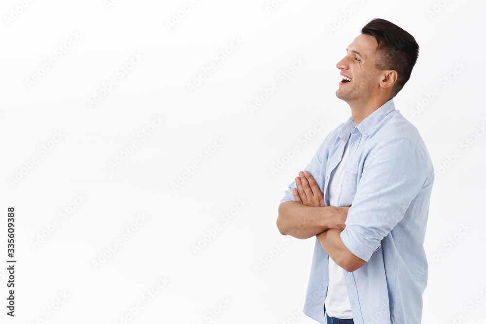 Profile portrait of handsome happy adult family guy in shirt, cross hands over chest, laughing and smiling pleased, looking left empty space at something adorable and funny, white background Profile portrait of handsome happy adult family guy in shirt, cross hands over chest, laughing and smiling pleased, looking left empty space at something adorable and funny, white background