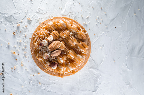 Delicious tart with caramel, almond and hazelnuts  on the white concrete background. Top view, flat lay, natural color grade