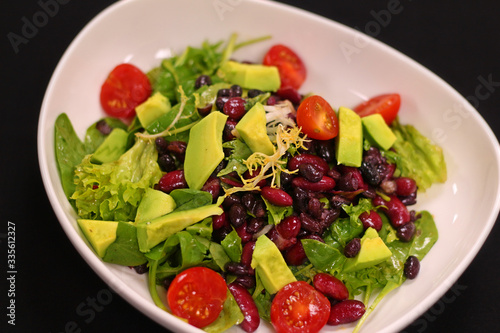 vegan salad with avocado, tomato, lettuce and black beans in a bowl