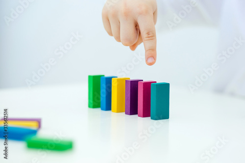 Building items in a single row. Concept of diagnostics of children's autism. A child plays with a colored wooden construction tool. Close.