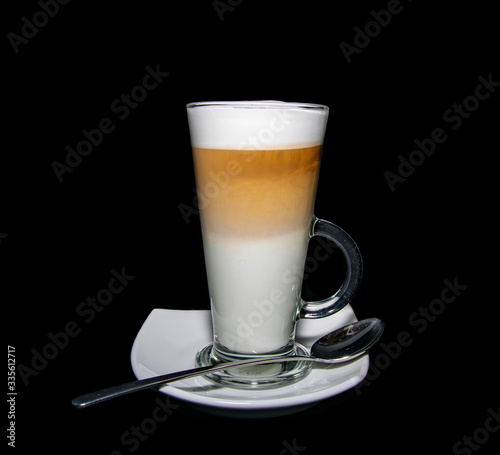 a finished triple layered latte coffee served with plate and spoon 