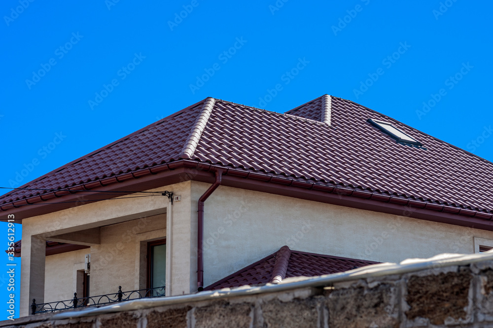 Brown Tiled roof of the house with windows on a background of blue sky