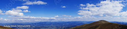 Panorama from Mount Hymba on a sunny day in late August. Top view of small mountains in the distance. Hanging clouds over the mountains. Carpathians  Ukraine  Europe.