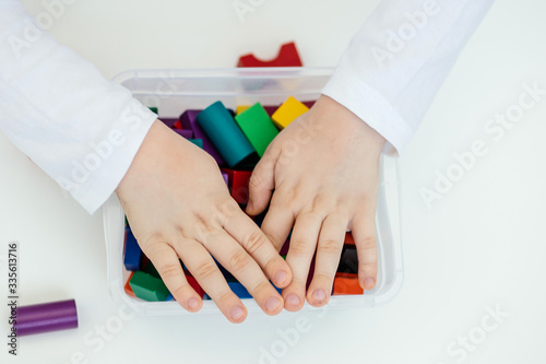 The child stereotypically plays with colored blocks of a wooden constructor. Concept of autism diagnosis and child development. Close.