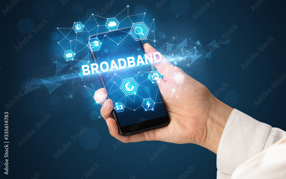 Female hand holding smartphone with BROADBAND inscription, modern technology concept Female hand holding smartphone with BROADBAND inscription, modern technology concept