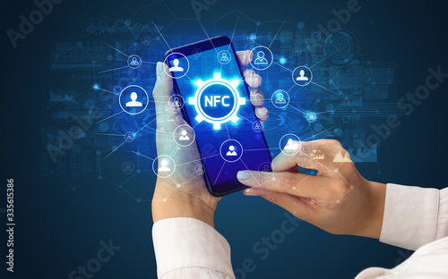 Female hand holding smartphone with NFC abbreviation, modern technology concept photo