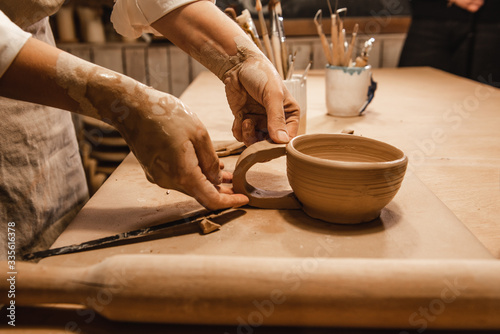 woman sculpts from clay a cup at the desk