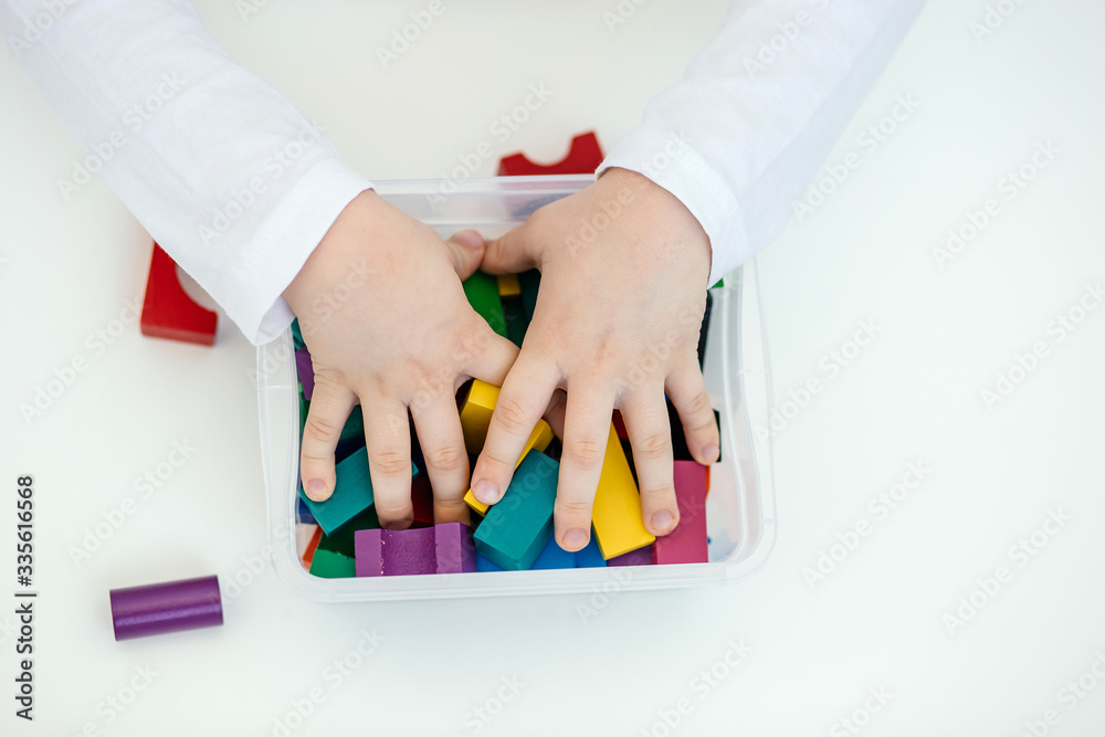 The child stereotypically plays with colored blocks of a wooden constructor. Concept of autism diagnosis and child development. Close.