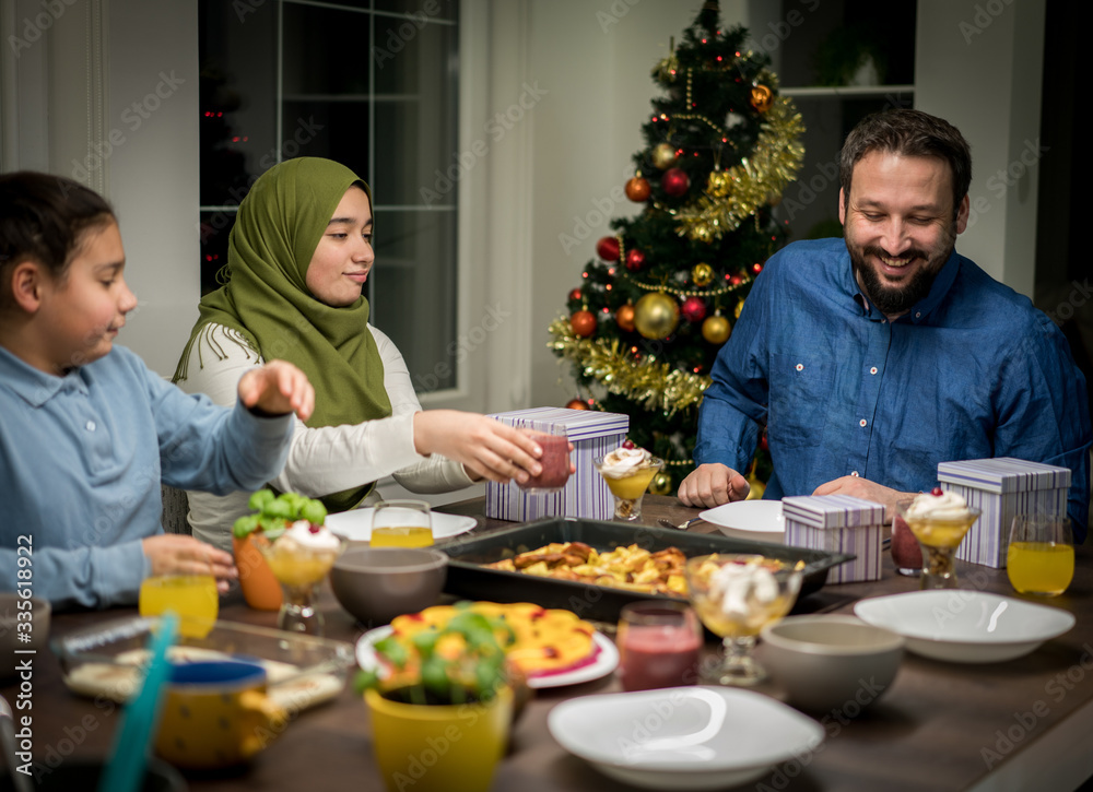 Muslim interreligious family with christmas tree in background