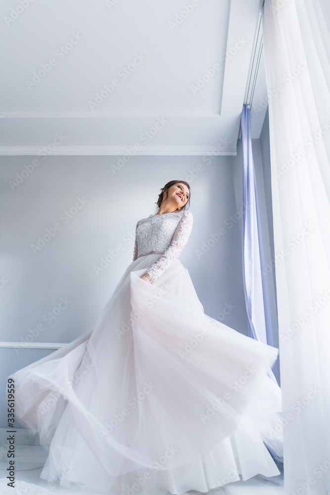 bride in elegant wedding dress whirling by the window. have fun. bride in elegant wedding dress whirling by the window. have fun.