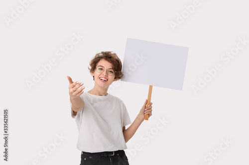 Smiling female protester holding empty signboard with copy space offering to join the protest. photo