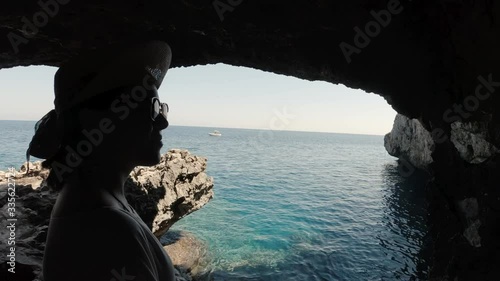 A young girl looking at the sea from inside a sea cave near Paphos, Cypris. A shot from the inside of a sea cave in the Meditteranean with a girl enjoying the calm sea waters. photo