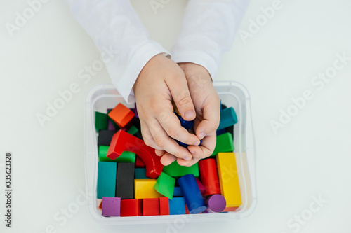The child stereotypically plays with colored blocks of a wooden constructor. Concept of autism diagnosis and child development. Close. © ferkhova