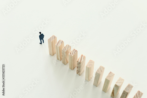 business concept. A man stands near dominoes and unaware of the danger of their fall. risk control and managment idea
