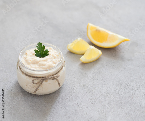 Appetizer white horseradish with lemon in a jar on a light background in rustic style