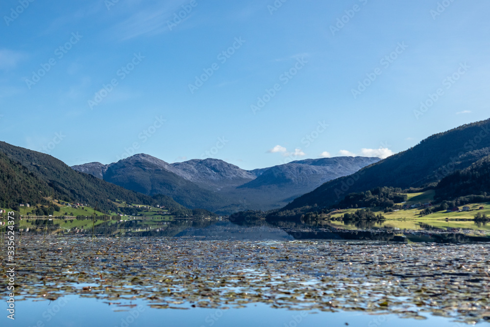 Norway mountains lake mirror on sunny day landscape. Hills reflection on water surface, blue sky, bright colors Norway mountains lake mirror on sunny day landscape. Hills reflection on water surface, blue sky, bright colors