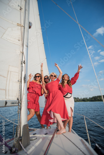 four girls in red and white clothes on the board, with good mood enjoy live and drink champagine.