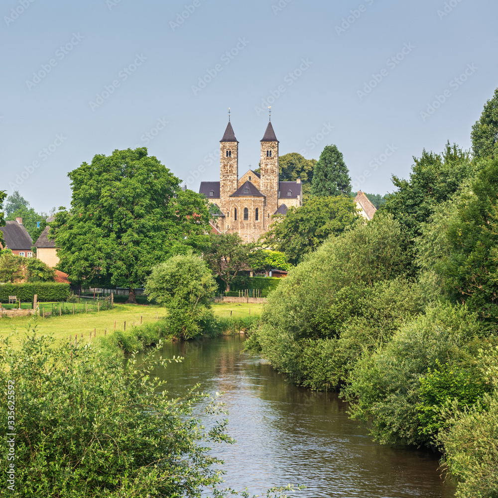 Nice view of the Romanesque basilica in Sint Odiliënberg village from the bidge over river Roer, Limburg, The Netherlands