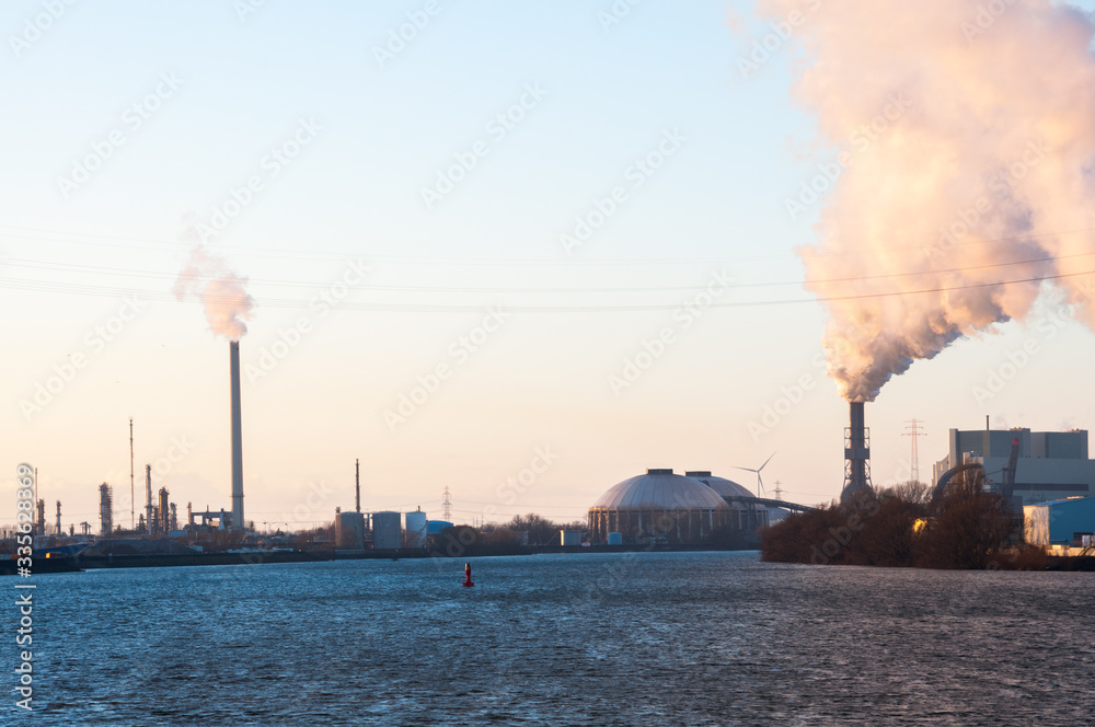 Smoking chimneys of industrial enterprise in the city on the river bank. Smoking chimneys of industrial enterprise in the city on the river bank.