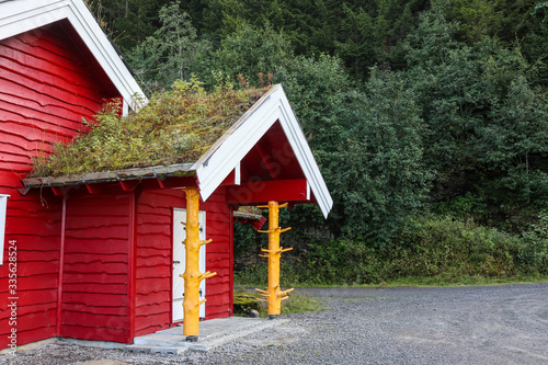 Fényképezés Red wooden traditional scandinavian green grass roof hut house in Norway