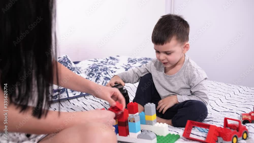 Mom and a little boy spend time together at home, collecting children's plastic designer Mom and a little boy spend time together at home, collecting children's plastic designer