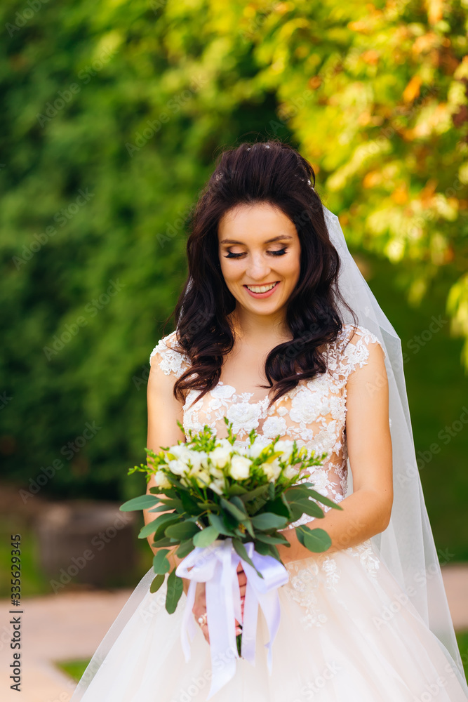 bride on a background of trees holding a wedding bouquet and smi